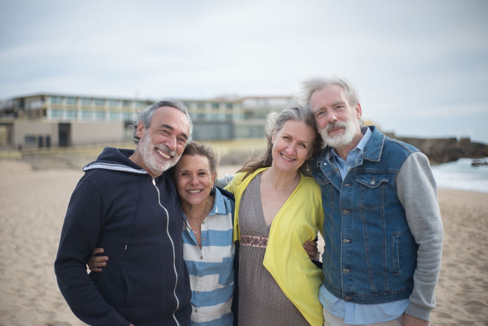 Four smiling older friends standing together on a beach, the company that makes Christian cruises for seniors special